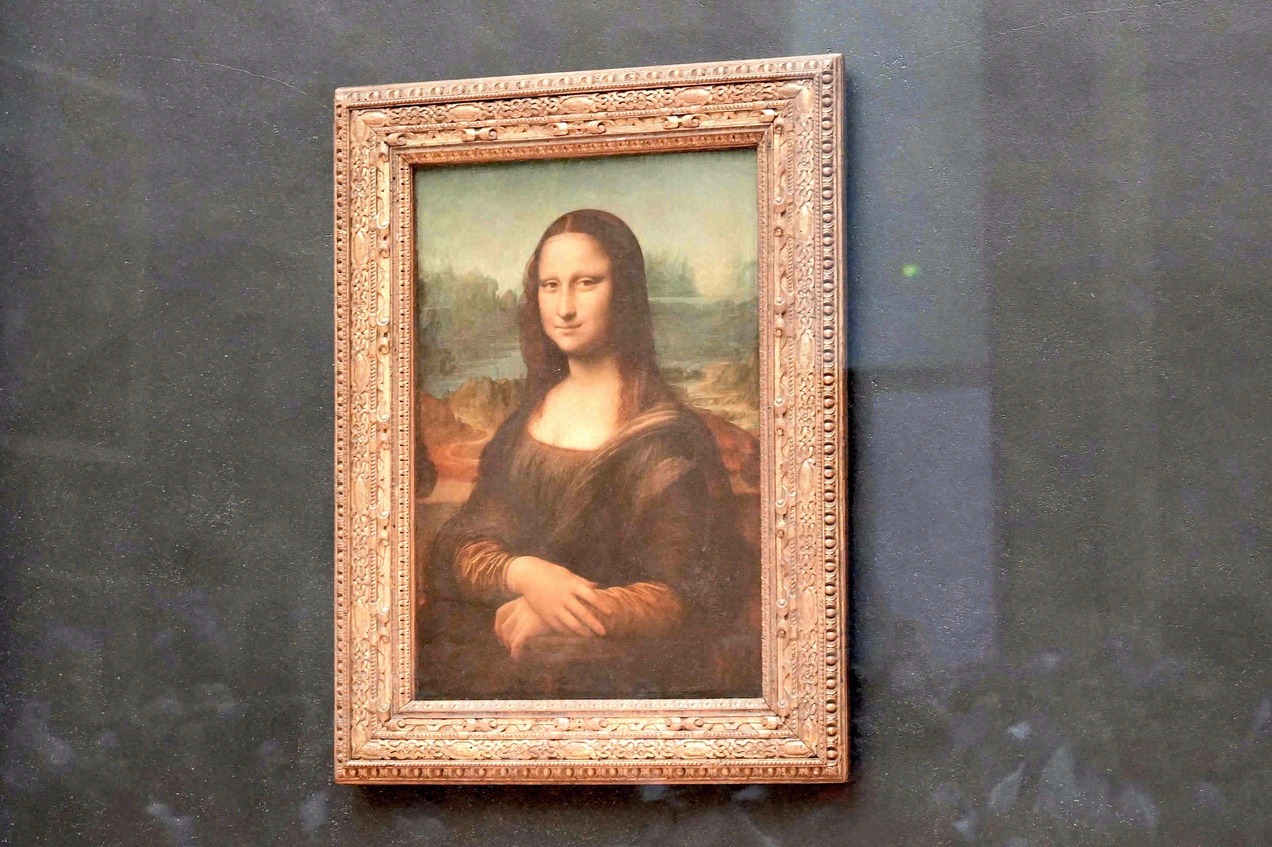 The Mona Lisa by Leonardo da Vinci, displayed behind glass at the Louvre, Paris.
